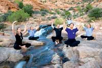Li Jun Feng and class meditating outdoors on rocks by a stream